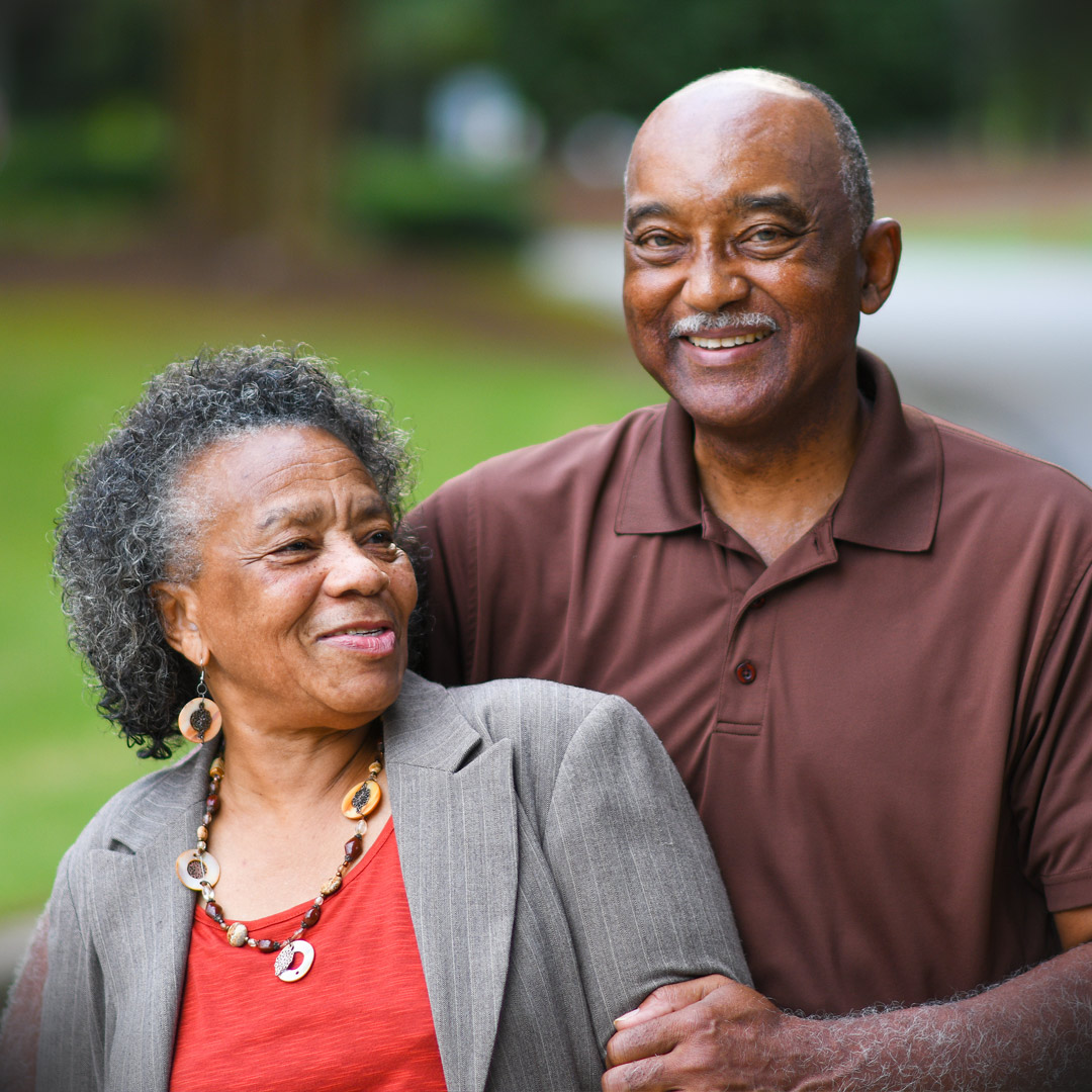 husband and wife standing together in front yard