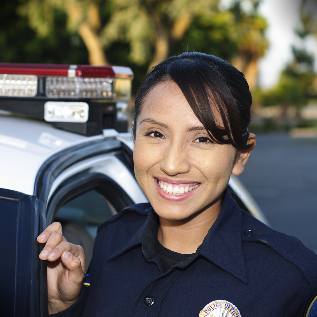 young police officer smiling in front of her squad car