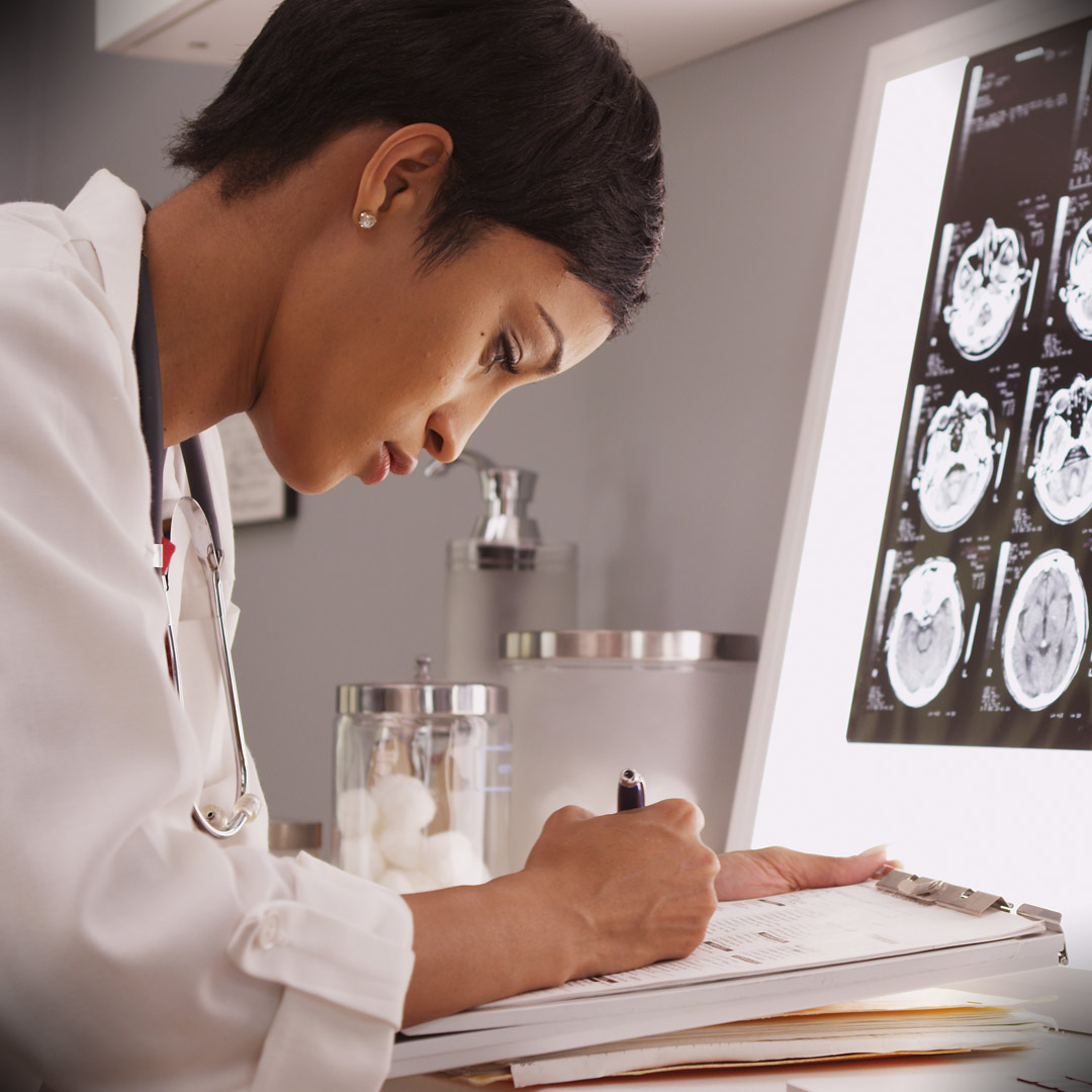 researcher making notes with brain scan in background