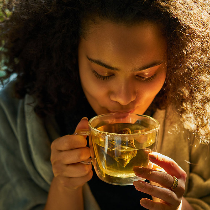 person drinking warm cup of tea from Teatulia