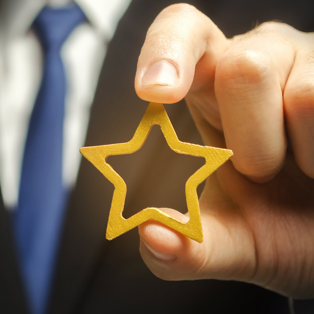 man in business attire holding gold star