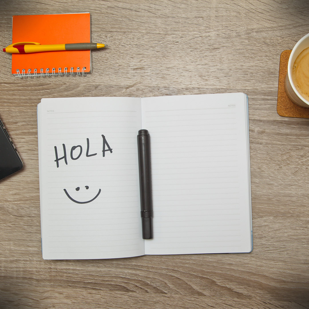 notebook with "Hola" and smiley-face written in it