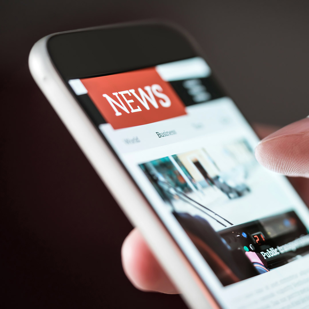 close-up of hand scrolling the news on a phone