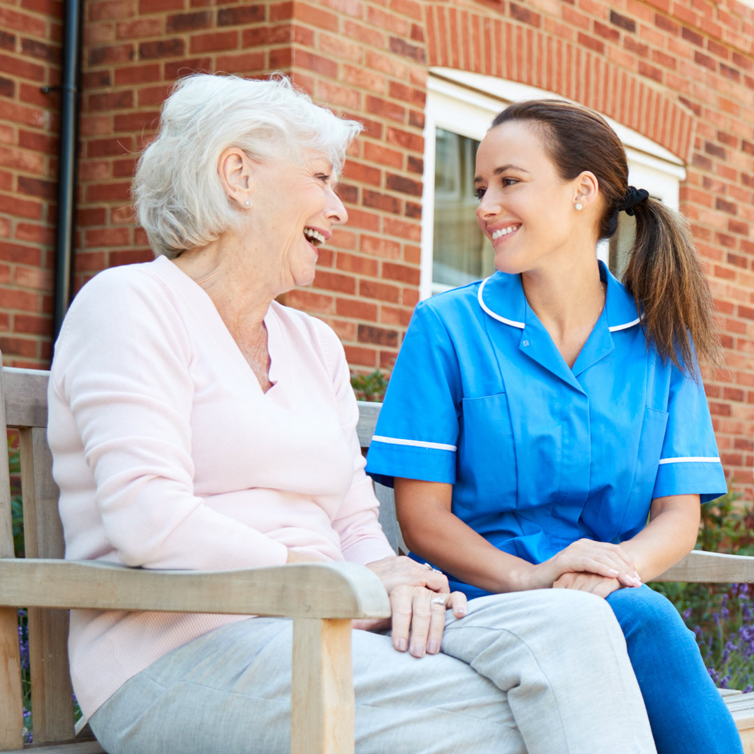 Caring-for-Someone-residential-choosing client and employee sitting together outside of residential care facility