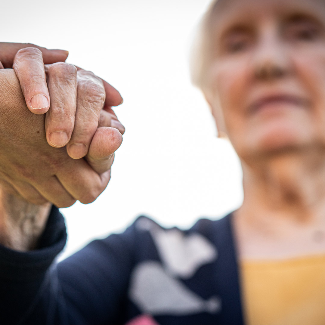 older woman clasping hands with someone gettinghelp