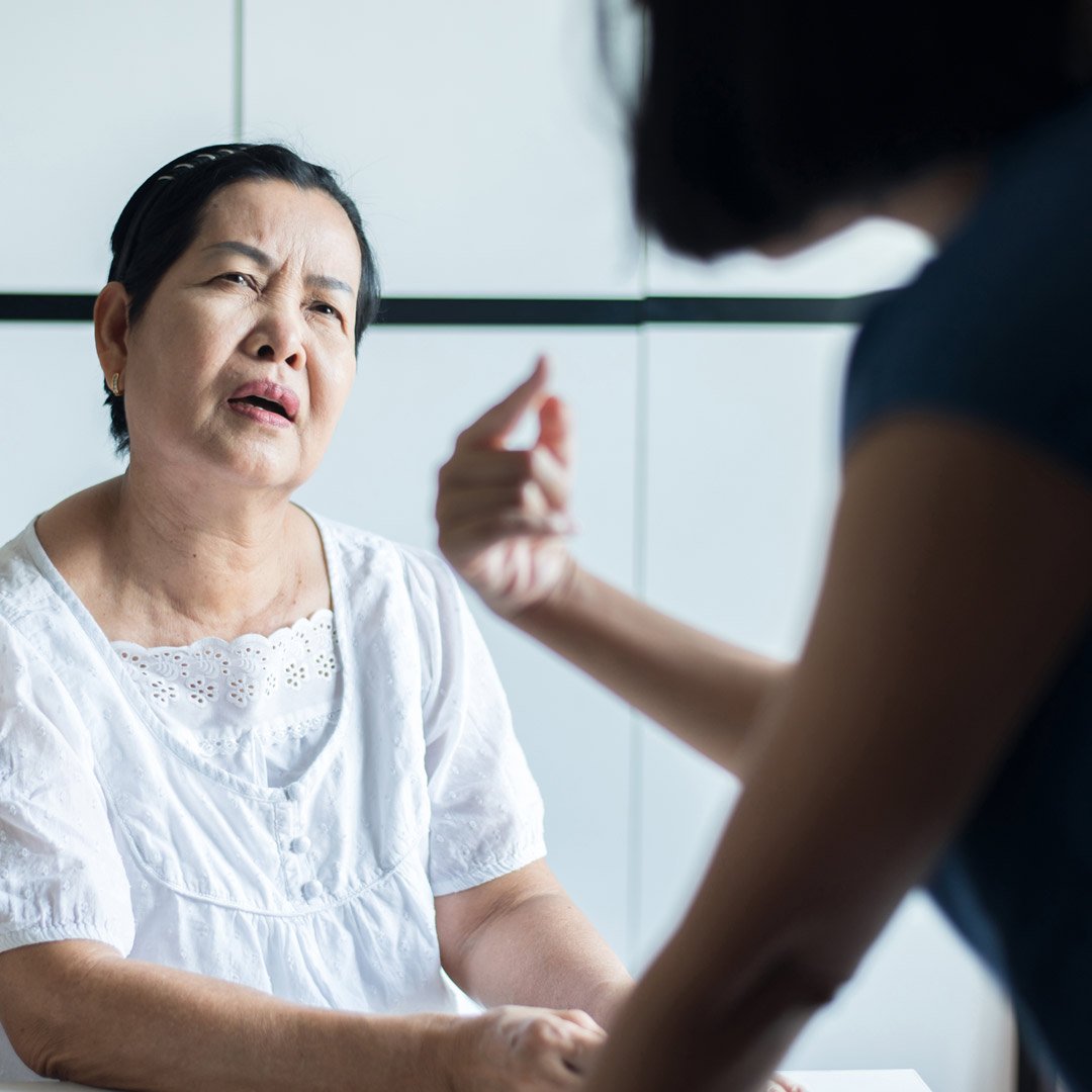 adult daughter looking at her confused mother and pointing at herself