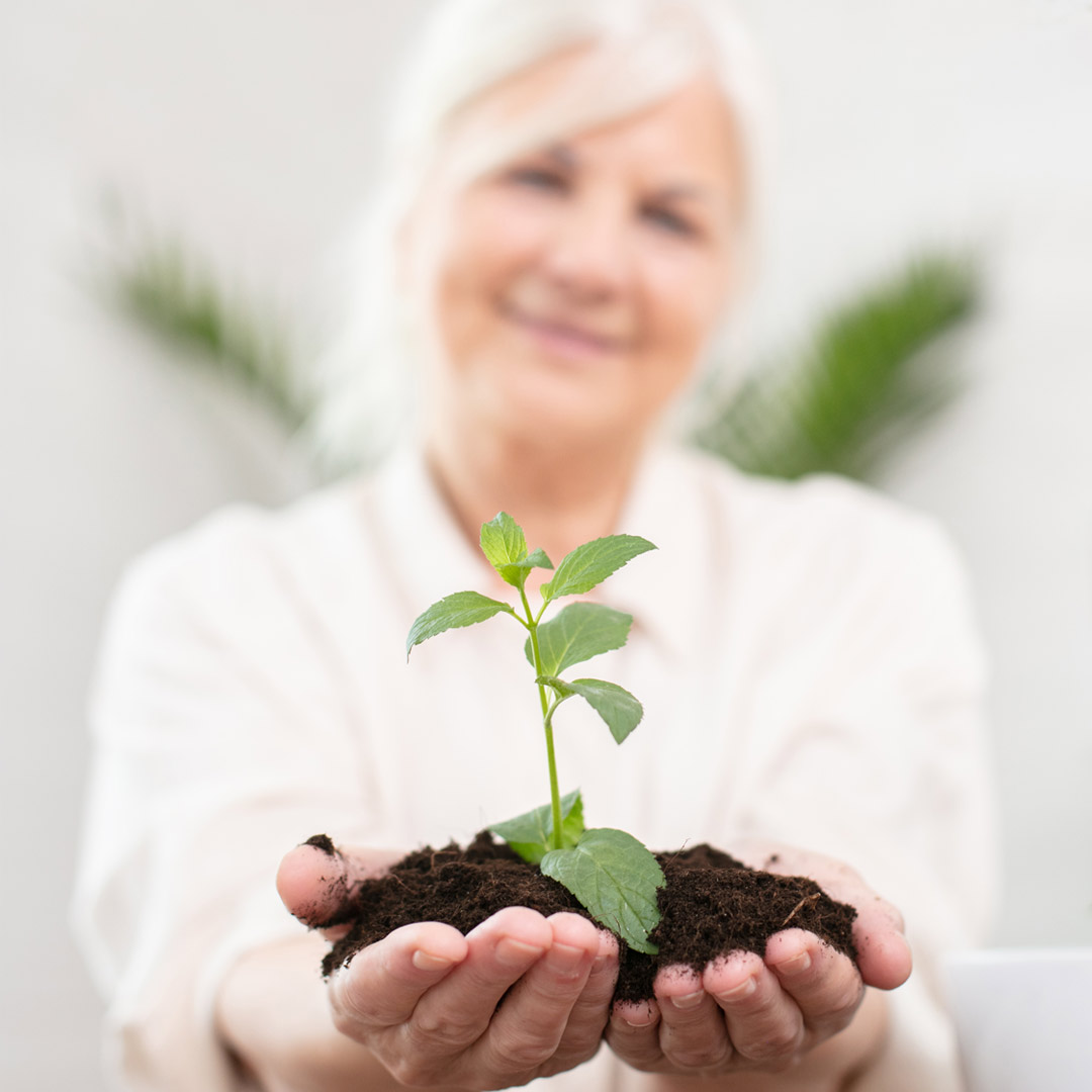 Get-Involved-ways-to-give-Planned-Giving woman holding newly sprouted plant