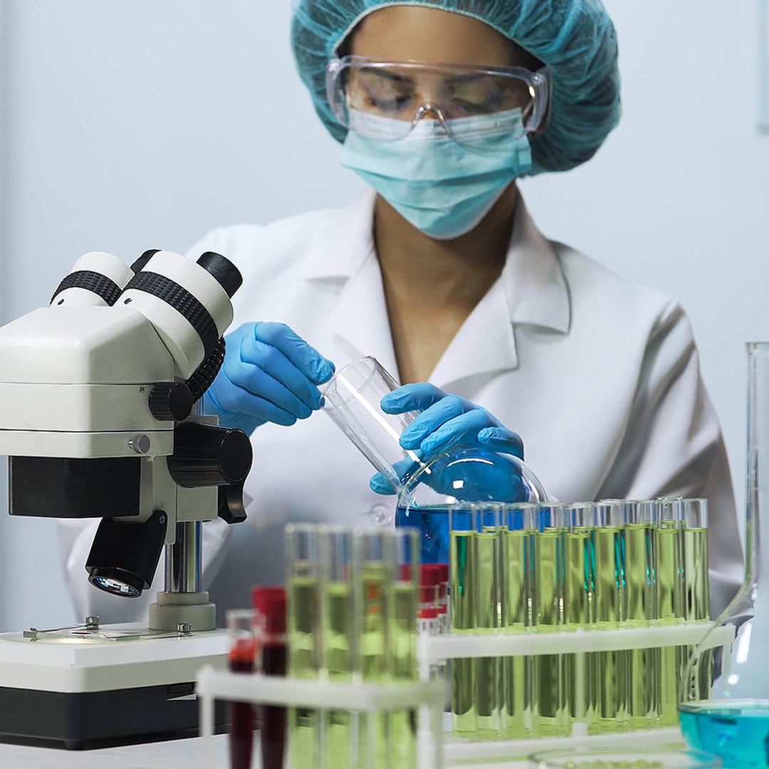 research scientist in lab with test tubes and microscope