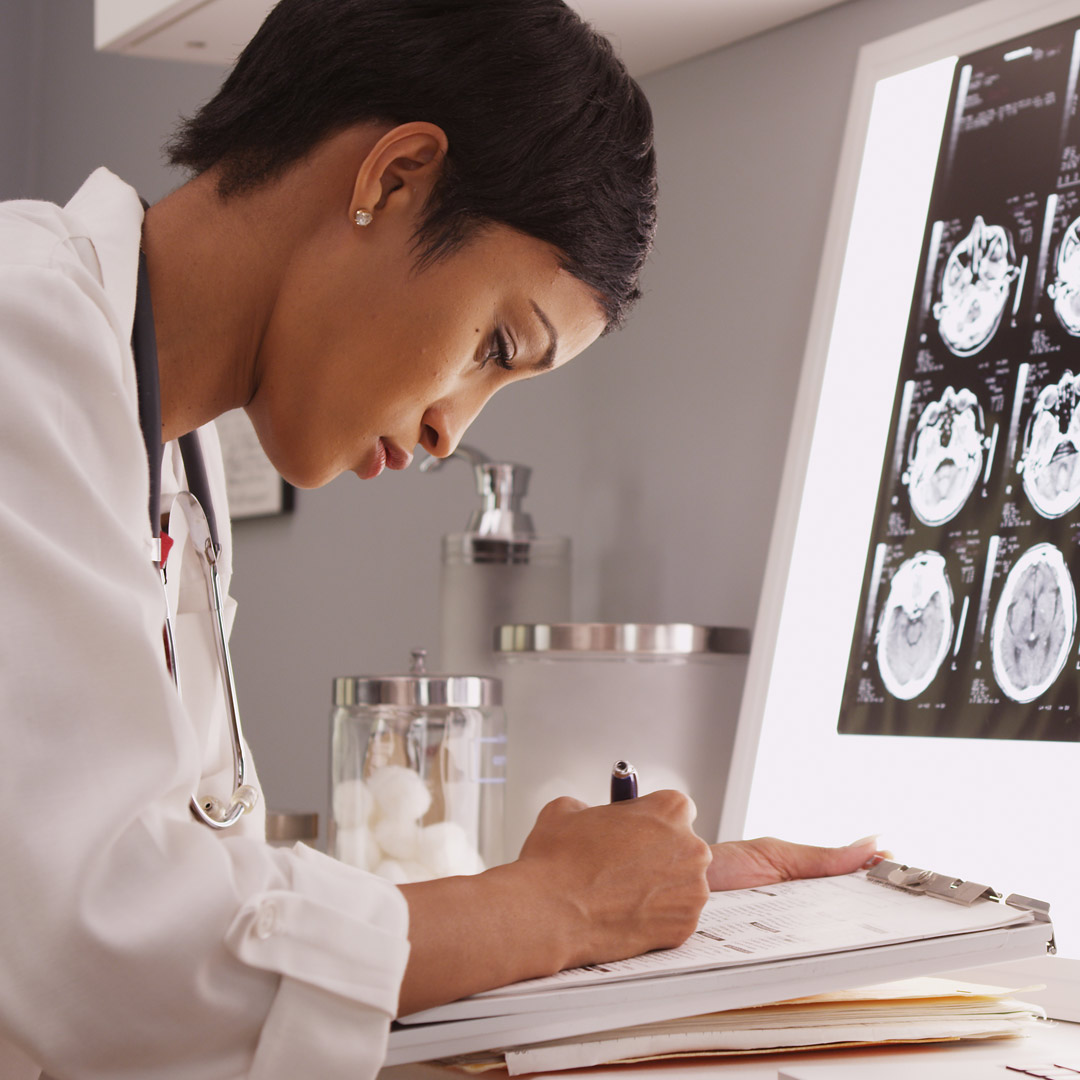 researcher in lab coat writing notes about MRI scan