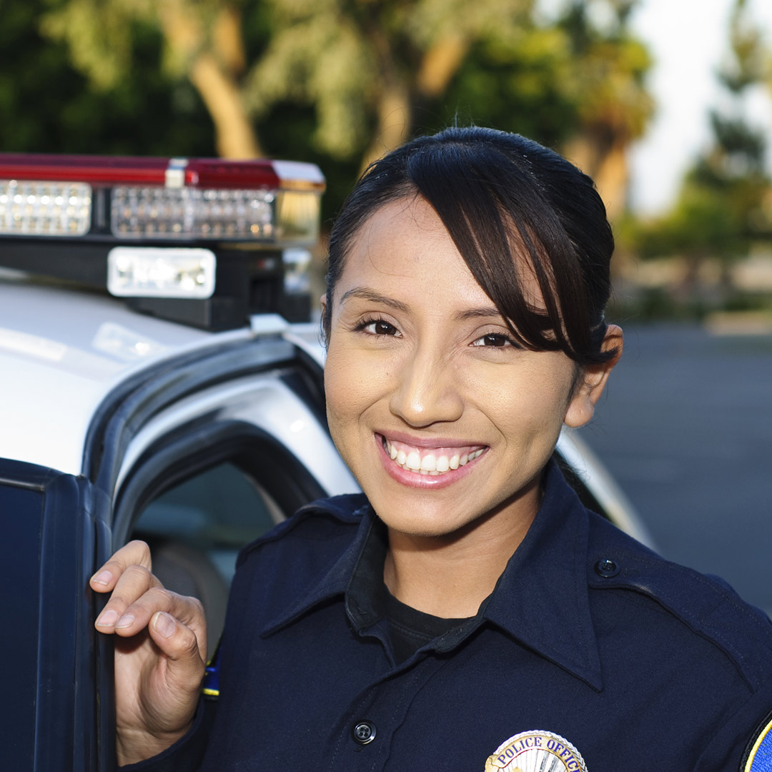 young police officer smiling in front of her squad car