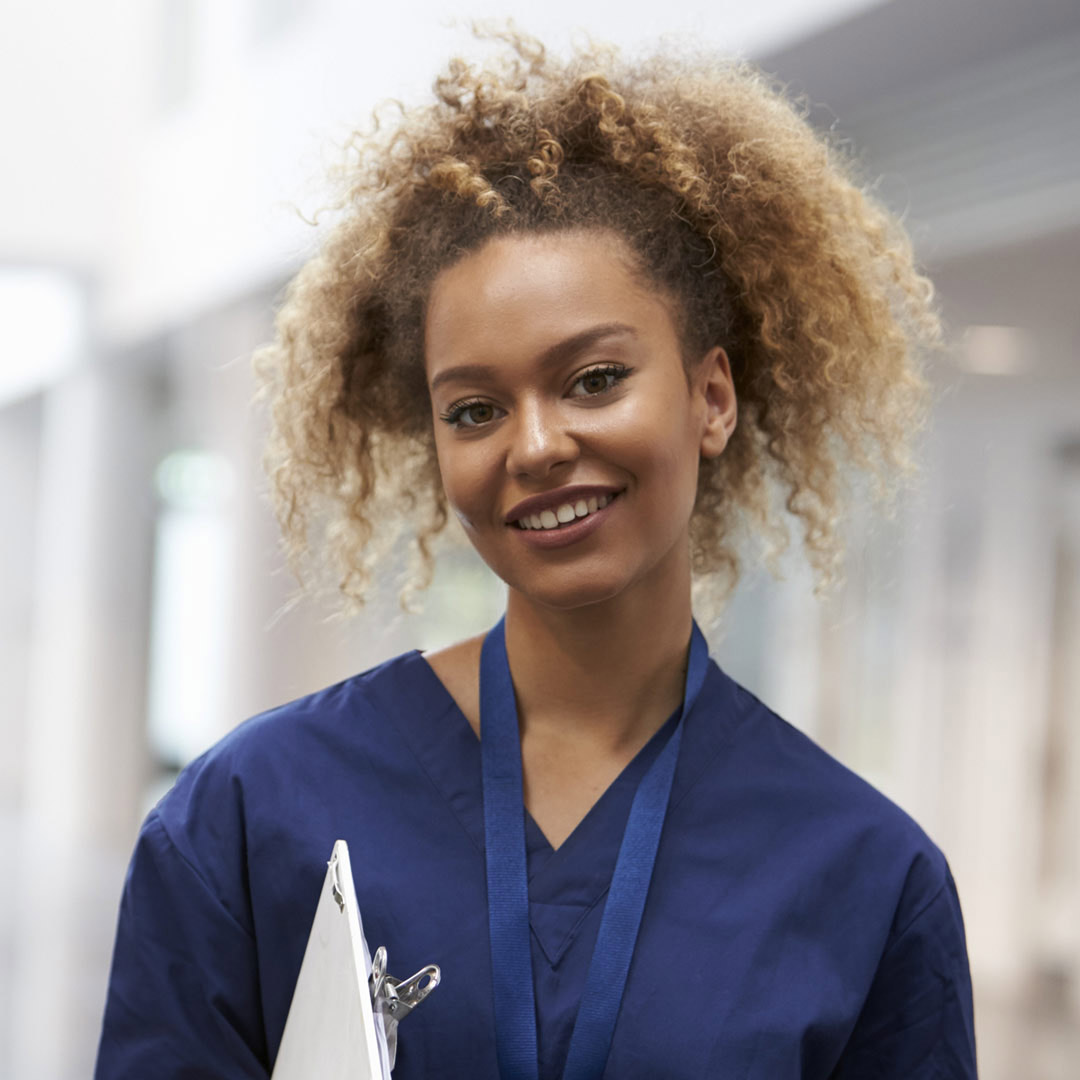 smiling healthcare worker in scrubs holding clipboard