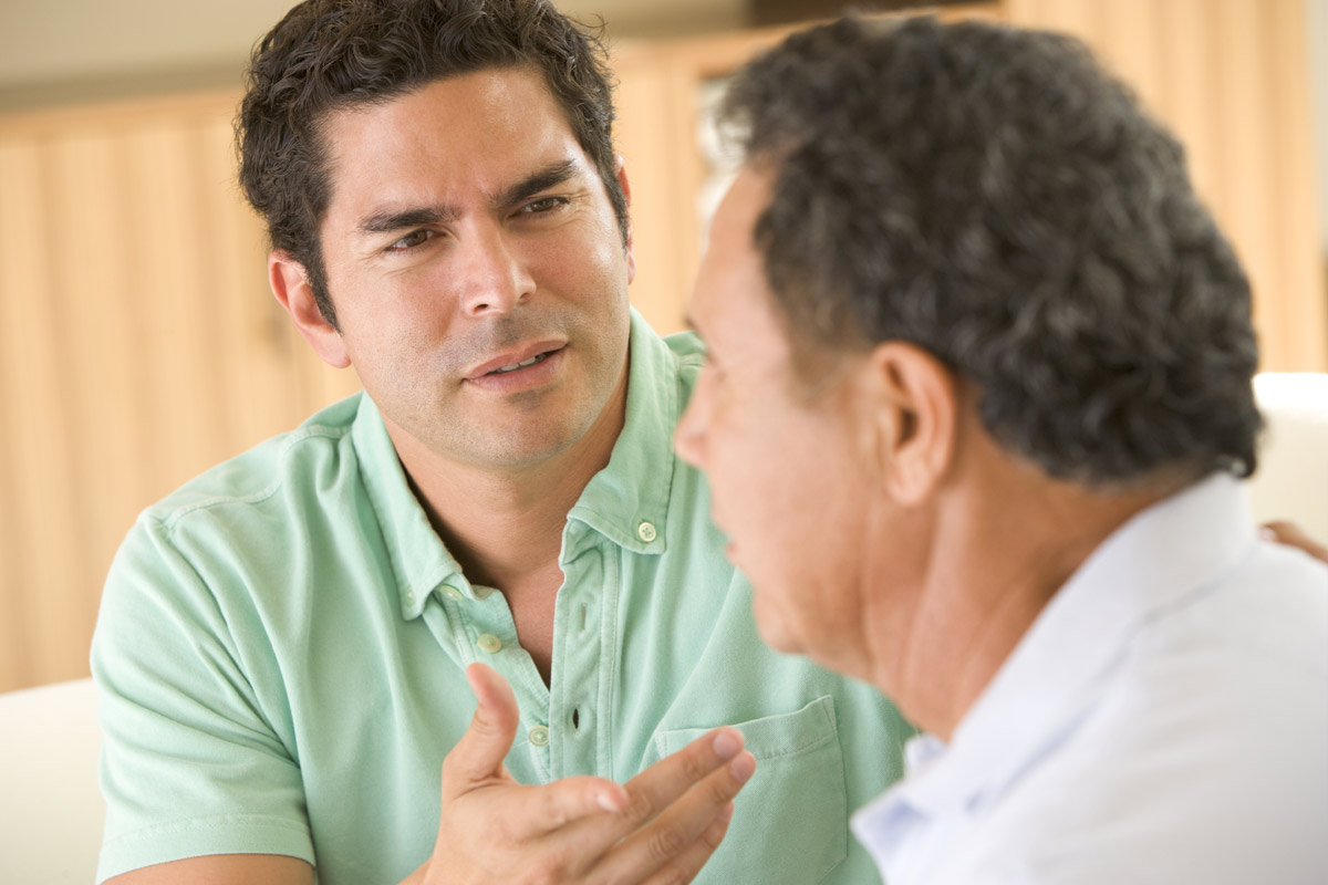 adult son with worried look talking with father