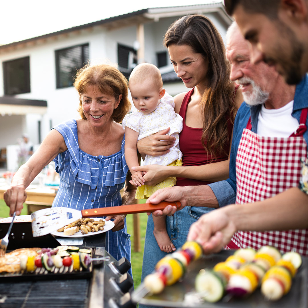 multigenerational family grilling vegetable skewers in backyard