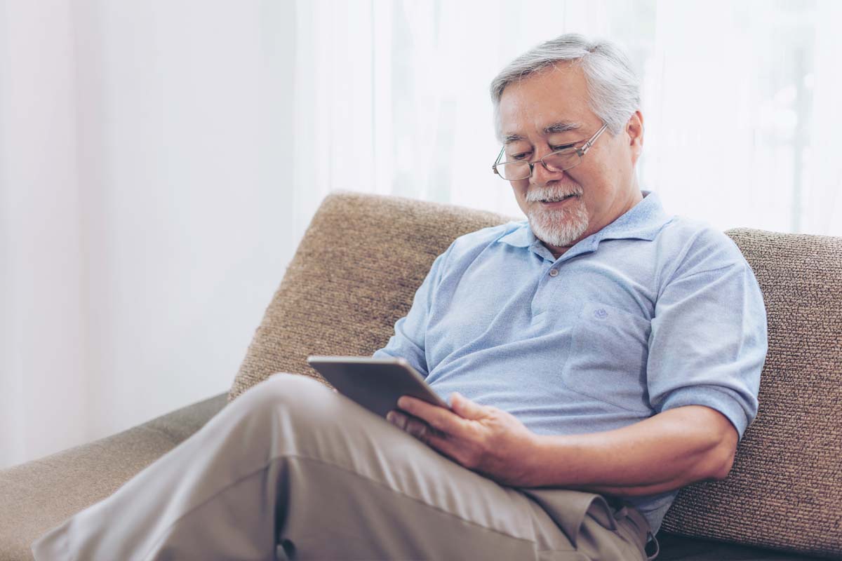 man sitting on couch looking at smartphone