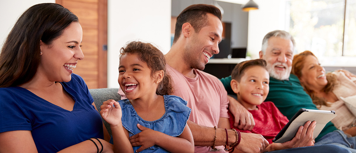 multigenerational family sitting on couch together and laughing