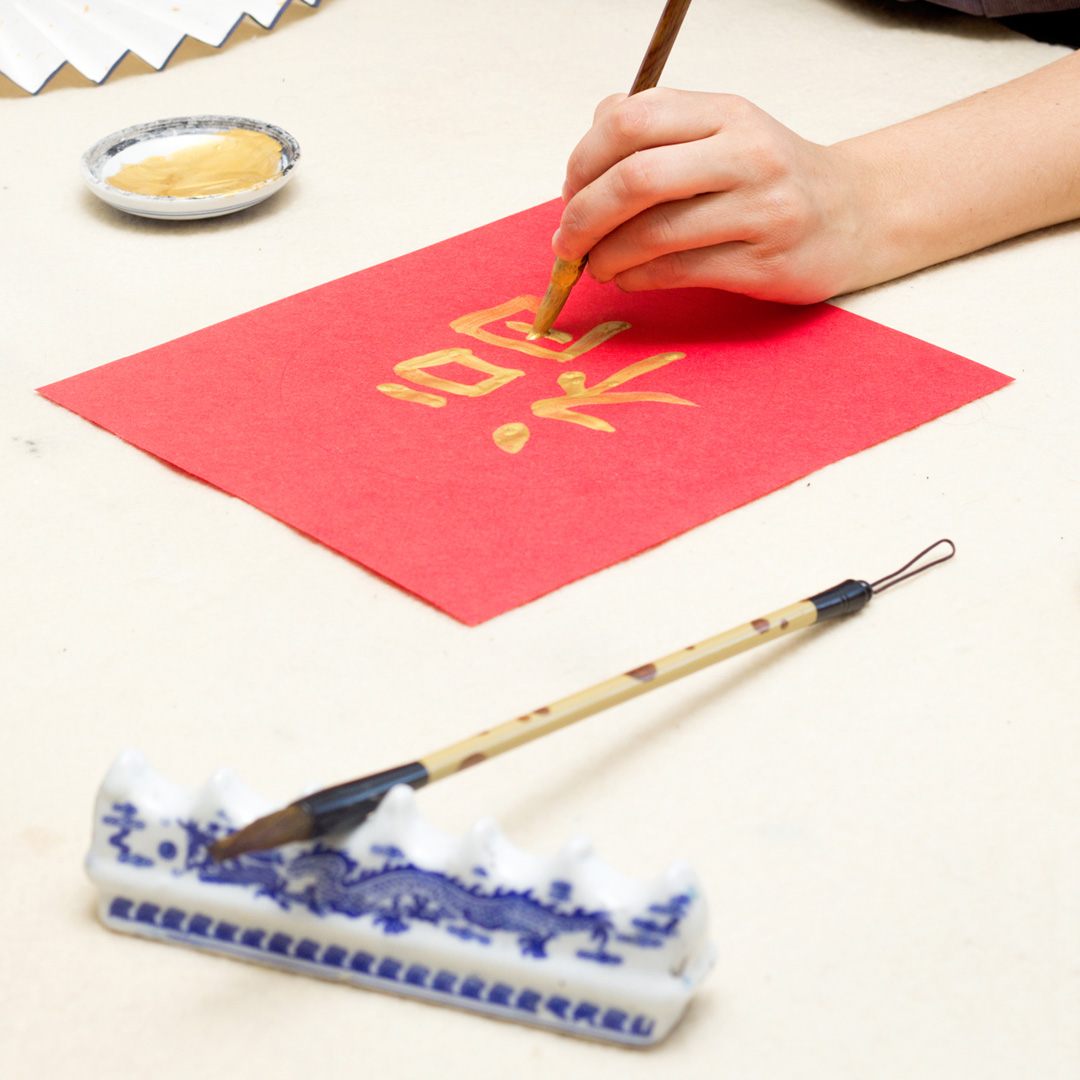 lunar-new-year-calligraphy close-up of hand writing Chinese character on red paper