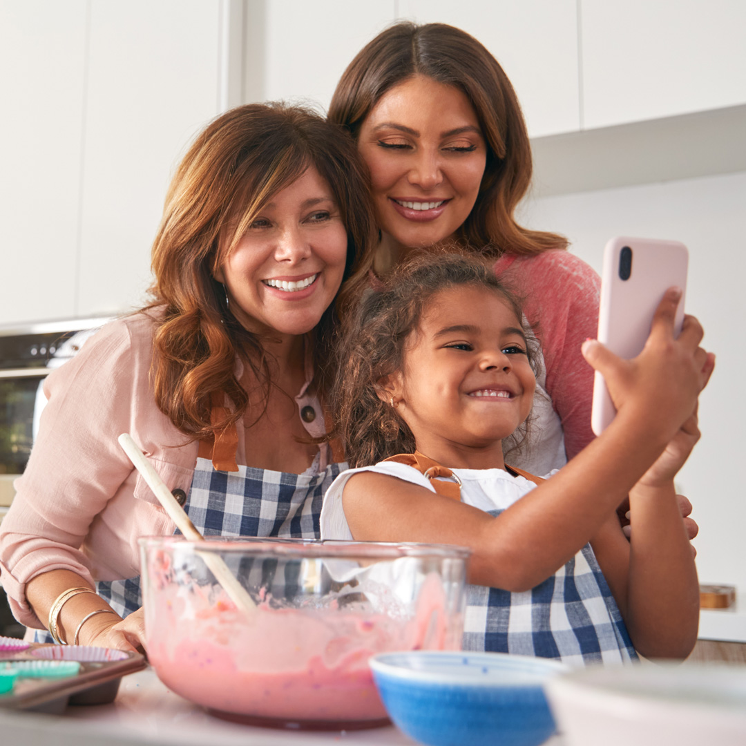 grandmother, mother, and granddaughter in kitchen taking a selfie