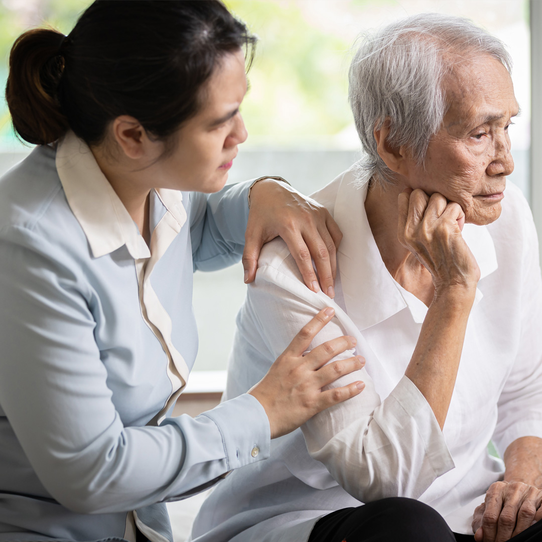 adult daughter trying to comfort father who is staring into the distance