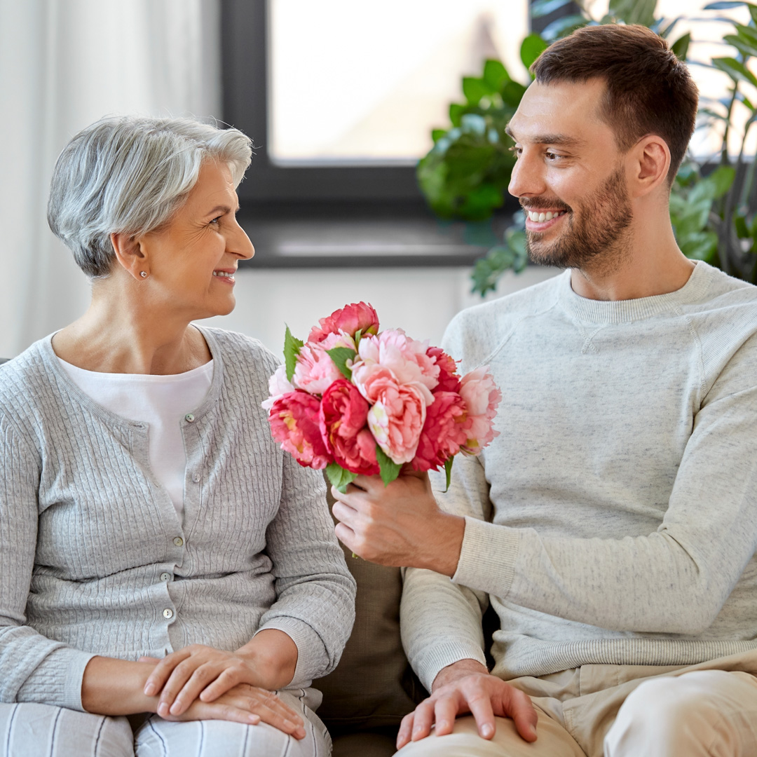 man giving his mother flowers