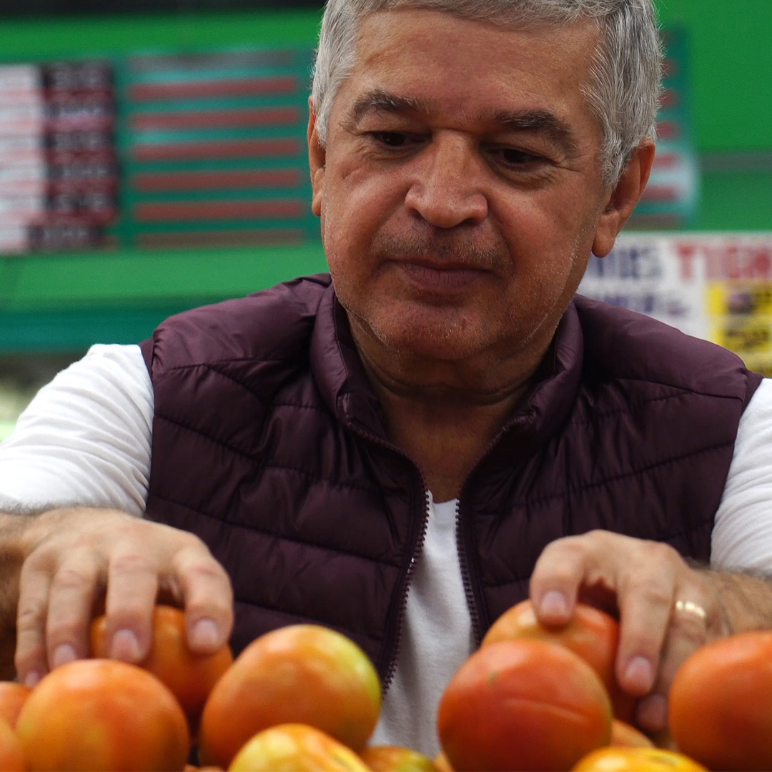 man trying to choose fruit at a grocery store