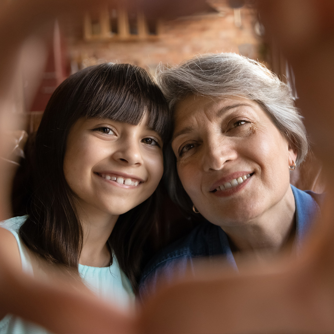 Grandmother and granddaughter putting hands together in heart shape