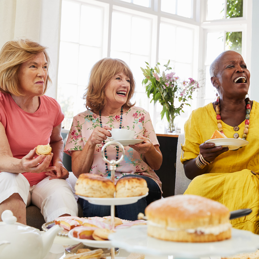 A group of friends laughing during an afternoon tea party held at home