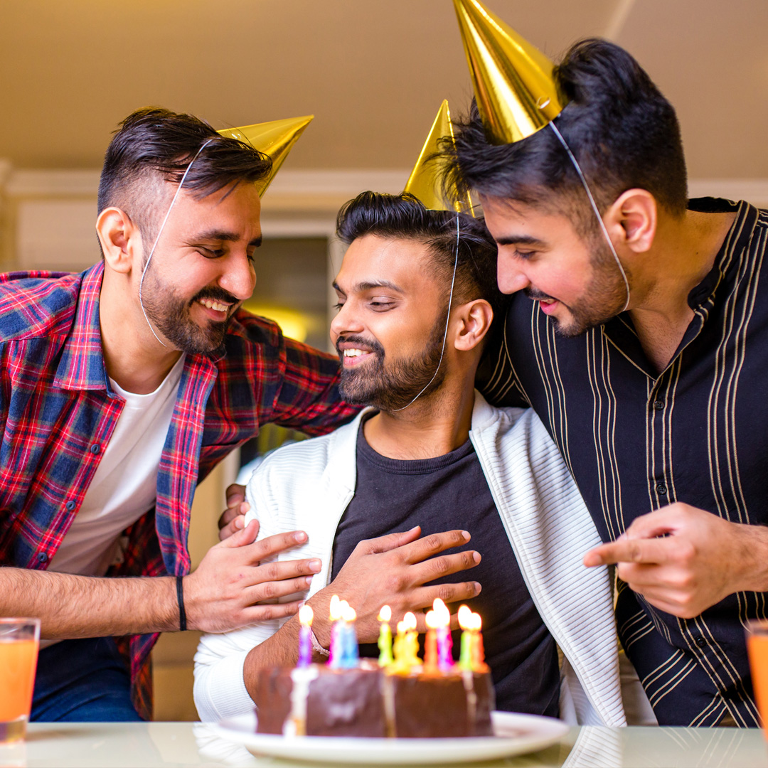 young man celebrating his birthday with two friends bringing him a cake