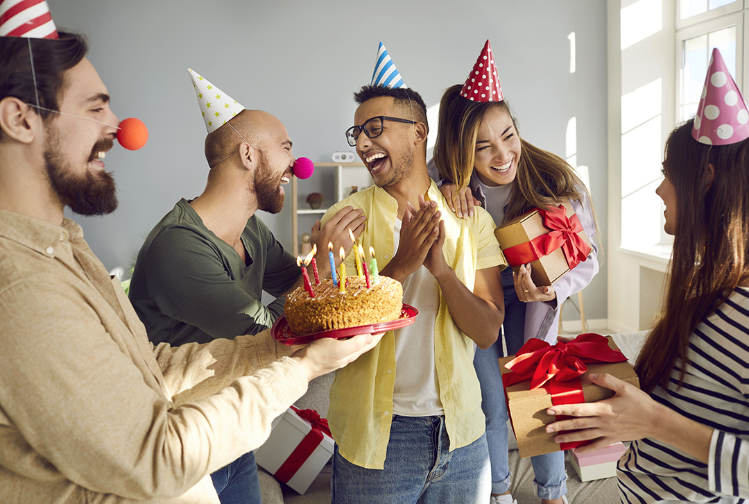 Adult friends laughing wearing birthday hats