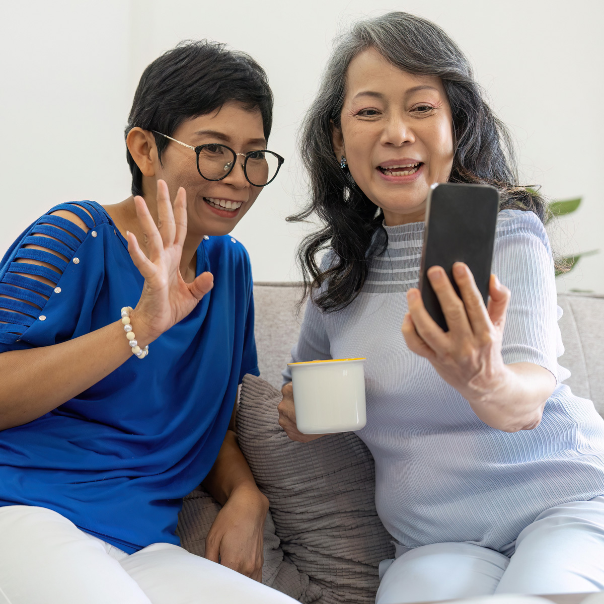 Two women looking at phone smiling and waving