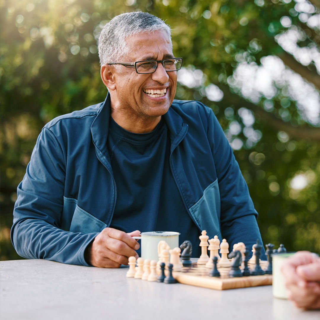 man playing chess in the park and smiling