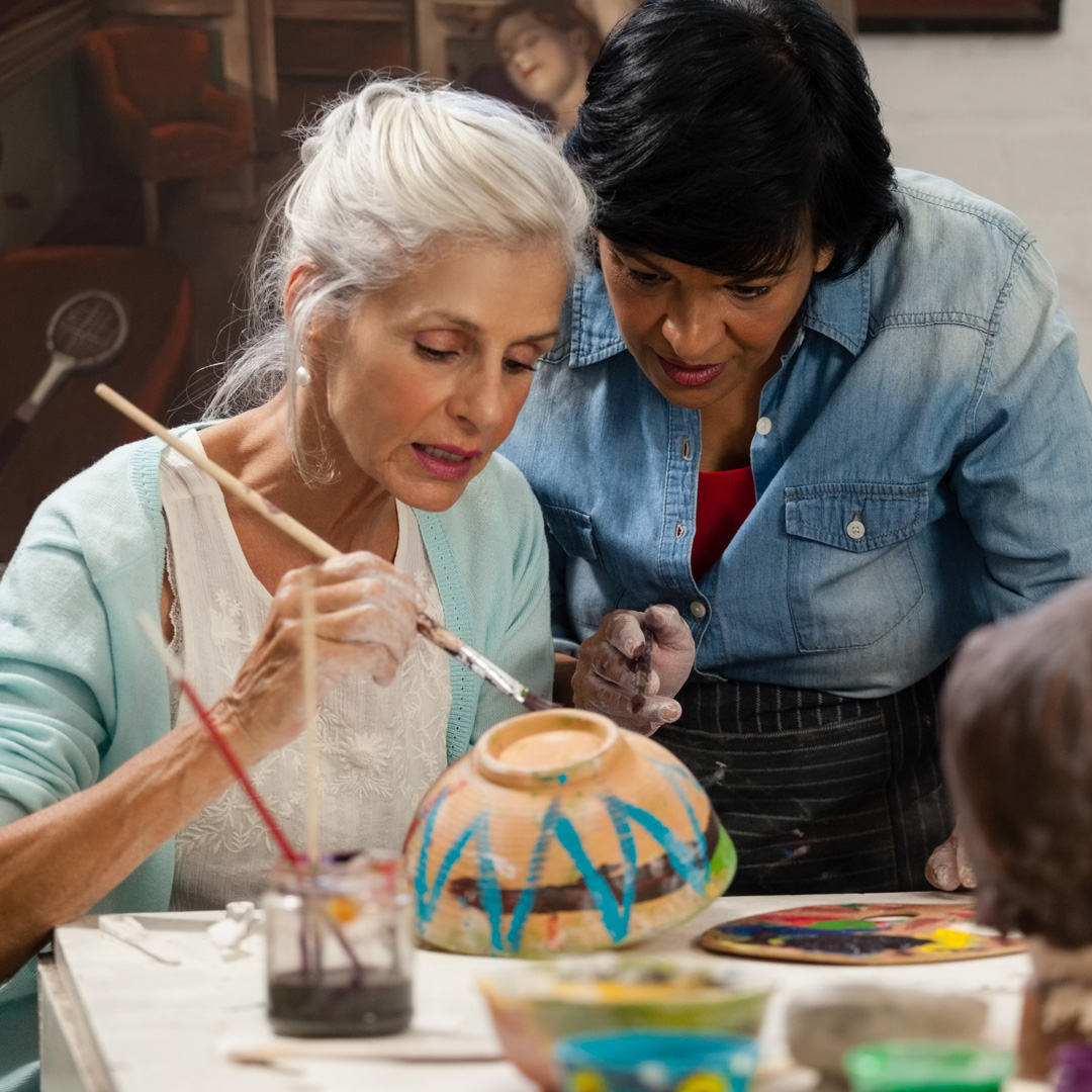 Care4ALZ-pottery-class-2 woman receiving instruction from a pottery teacher