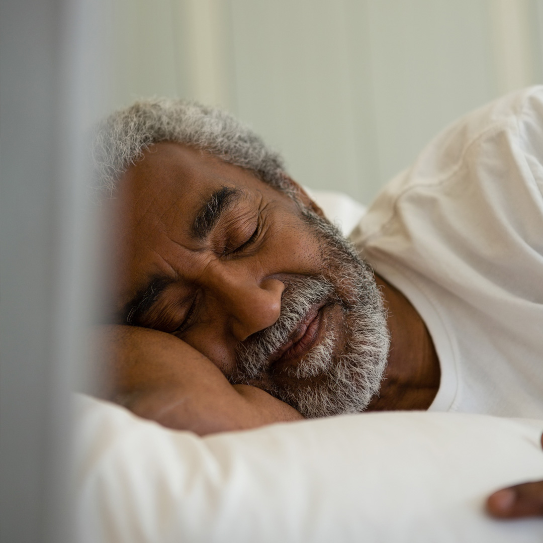 man lying on his side in bed sleeping peacefully
