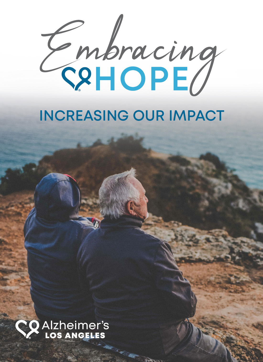 two people sitting on a cliff looking out into the ocean