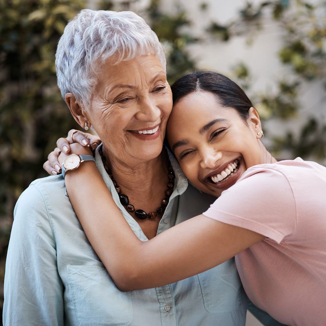 Adult daughter hugging mother and smiling